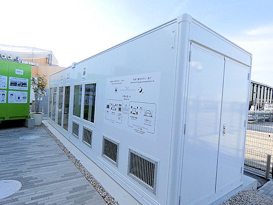 (写真1)NTTパビリオンの裏に置かれた、水素を生成する水電解装置と水素を保存する水素吸蔵合金タンクが設置されたコンテナ。このコンテナは、清水建設が提供する「Hydro Q-BiC Lite」で、発電に必要な水素2日分を蓄えている。 イメージ